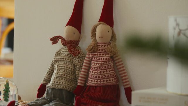 Two decorative christmas elves sitting on shelf in cozy home interior.