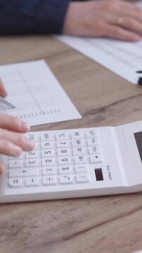 Office worker balancing budget with calculator and laptop on a desk. Bookkeeping, finance audit and taxes