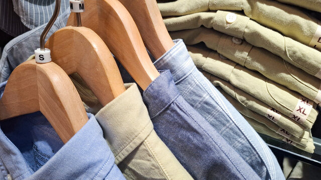 Folded and hanging shirts organized on display with size tags in a clothing store retail environment
