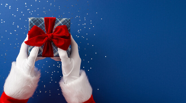 Merry Christmas and Happy New Year from Santa Claus offering a wrapped gift with a red bow