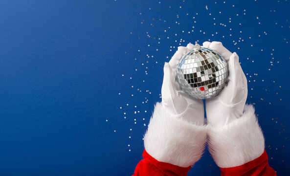 Merry Christmas and happy New Year from Santa Claus holding a sparkling disco ornament