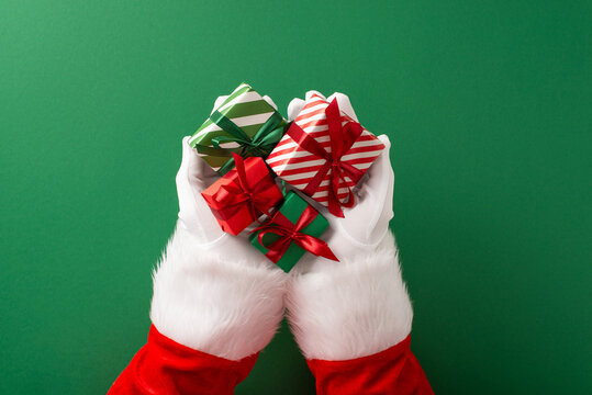Merry Christmas and happy New Year from Santa Claus holding a small wrapped gift in white gloves