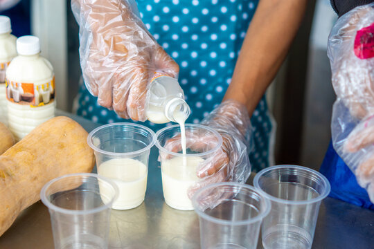 A small business employee is preparing soy milk (Soya milk, Soybean milk, susu kedelai, Doujiang, soy drink) for a customer.