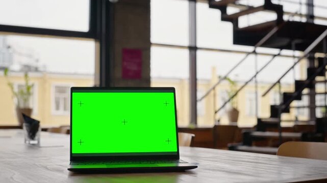 Modern laptop displaying green screen mockup with tracking markers resting on cafe table. Footage perfect for software replacement, remote work advertising, and UI demonstration
