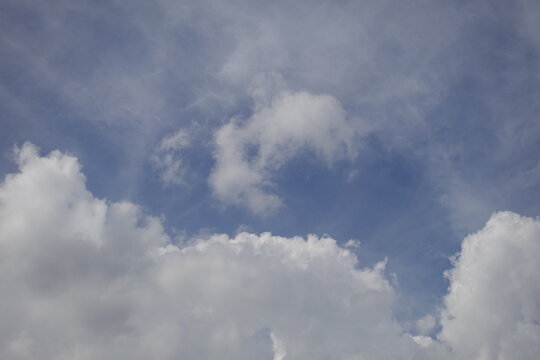 Fluffy white cumulus clouds rolling across a bright blue sky on a sunny day