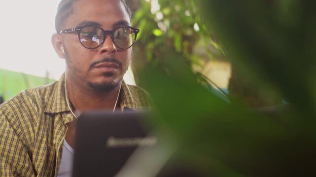 Focused african freelancer wearing eyeglasses working on laptop