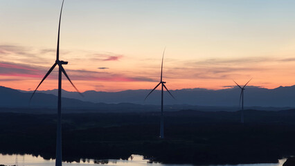 Obraz premium wind turbines silhouette against colorful sunset sky