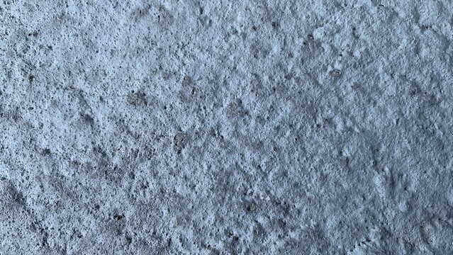 Close-up of a rough concrete wall surface showing porous texture, weathering, and natural construction material details