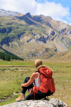 female hiker resting on rock admiring mountain valley view, Pyrenees