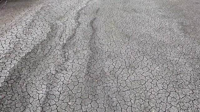 A slow high-angle forward camera movement glides over intricate cracked dried mud and soil textures on a lake bed surface, highlighting arid ground patterns in scenic Als&oacute;mocsol&aacute;d, Hungary, Europe.