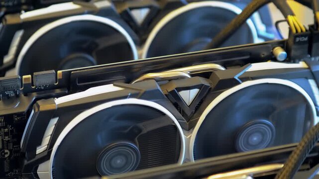 Diagonal closeup shows several graphics cards operating with fast dual fans metal heat pipes and a braided power cable crossing an open GPU mining rig