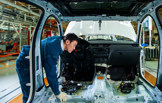 Car factory workers inspect cars on the assembly line