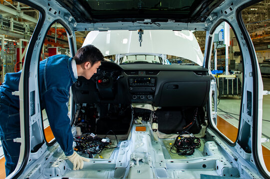 Car factory workers inspect cars on the assembly line