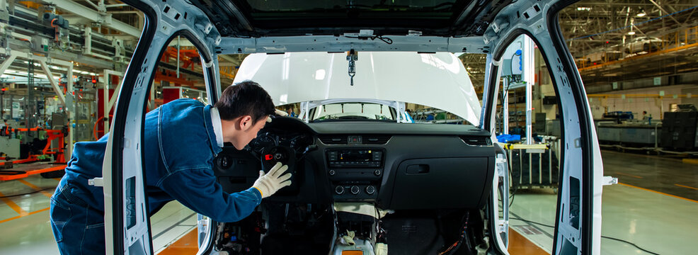 Car factory workers inspect cars on the assembly line