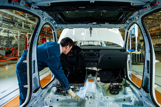 Car factory workers inspect cars on the assembly line