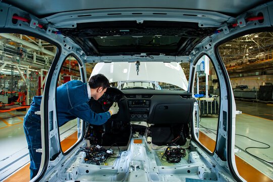 Car factory workers inspect cars on the assembly line