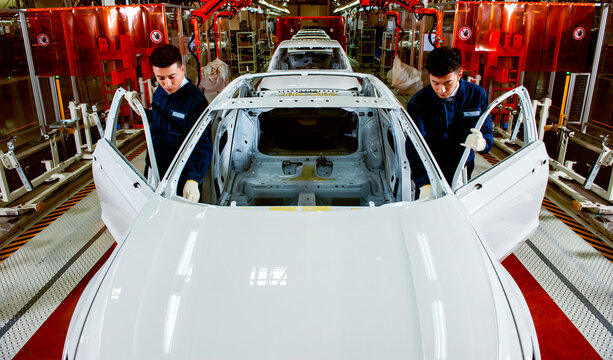 Two Factory Workers Inspecting Body in White on Automotive Assembly Line