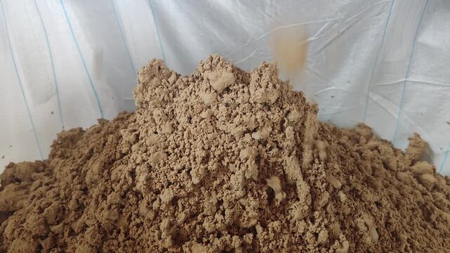 Dried Industrial Sewage Sludge Cake Falling into Big Bag from Treatment Plant Conveyor.