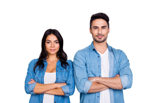 He vs She portrait of caucasion hispanic couple in jeans shirt - man with bristle and pretty, attractive woman with crossed hands standing over grey background