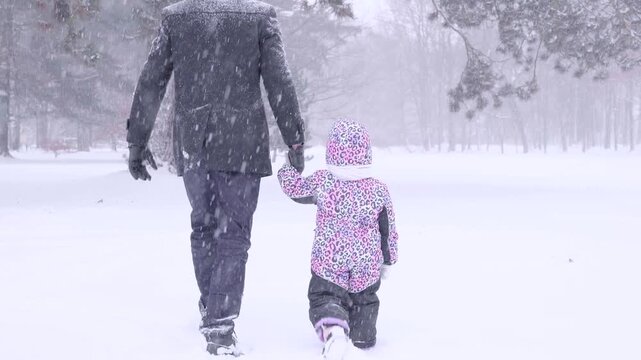 Father playful moment. Toddler having fun in winter landscape. Joyful childhood concept.
