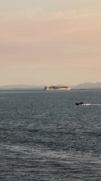 Pacific Ocean navigation &ndash; a cargo ship arrives to the Port of Vancouver against a beautiful mountains and blue sky. Wide shot, real-time footage. - Vancouver, BC, Canada 