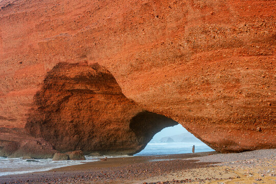 Woman standing under Ali Aman arch in Lagzira beach, Morocco