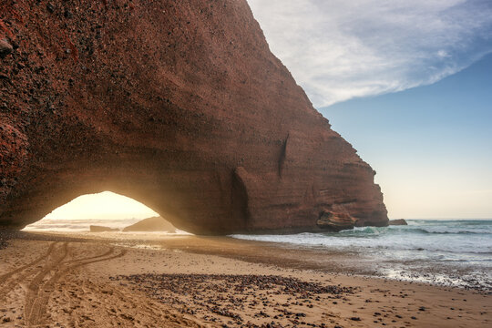 Ocean waves eroding red sandstone rock formation at Lagzira beach arch