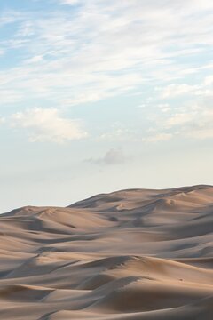 Endless rolling sand dunes under a soft blue sky in Sahara Morocco