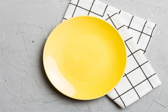Top view on colored background empty round yellow plate on tablecloth for food. Empty dish on napkin with space for your design