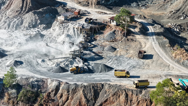 Industrial stone crushing plant operating with heavy equipment in a dusty quarry environment