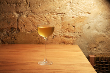 Chilled cocktail glass with golden drink on wooden table in bar setting © Gecko Studio