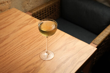 Chilled cocktail glass with golden drink on wooden table in bar setting © Gecko Studio