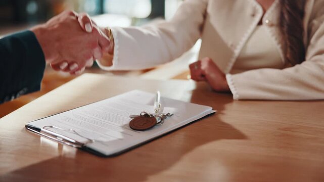 Keys, handshake and signature in house with document, lease contract and form for administration. People, legal paperwork and shaking hands for rental agreement in home with policy, mortgage or loan