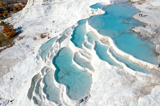 Aerial view of travertine terraces with turquoise pools in a natural landscape