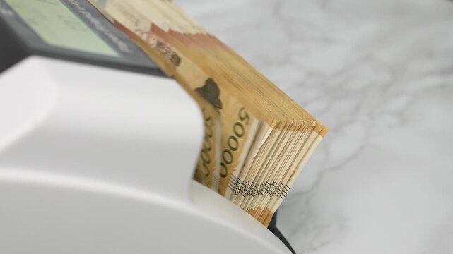 Close-up Fixed Shot of Money Counting Machine Counting 100 Crisp 50,000 Won Banknotes (Cash, Banking, Finance)