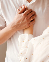 Obraz premium Close view of husband and wife holding hands against his chest in a tender gesture. Intimate moment representing marriage, love, trust, emotional support and connection between spouses.