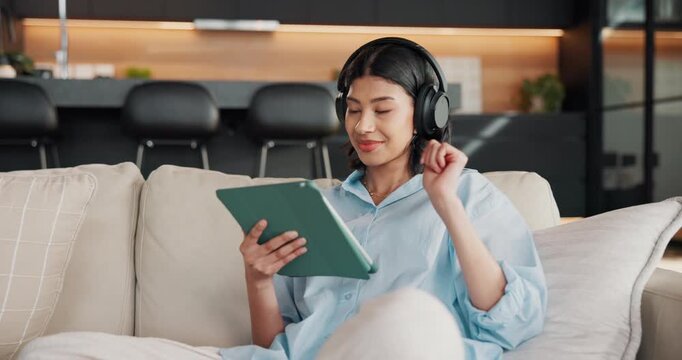 Woman, headphones and scroll in home with tablet, browsing social media and listen to music playlist. Happy, person and relax in lounge with audio tech, streaming radio and reading blog on website.