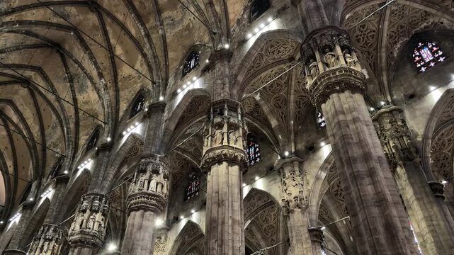 Milan, Italy - May 05, 2026: Gothic cathedral interior with towering columns, intricate arches, and illuminated stained glass windows showcasing architectural beauty