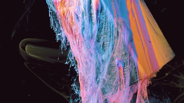Viscous colored paint peels and flows off rectangular surface into layered sheets, filaments, and separating droplets against deep black background