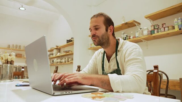 Potter managing small business using laptop