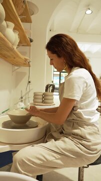 Woman shaping clay on a pottery wheel in a ceramic workshop