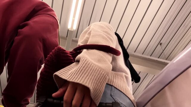Slow motion low angle video of a young Asian couple pushing a cart together in a supermarket aisle. Shot from inside the trolley looking up at them.