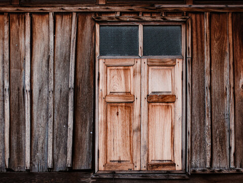 Wooden double door with frosted glass panels on plank wall