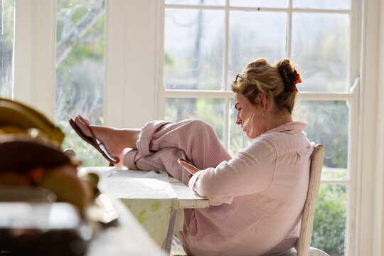 young woman relaxing in chair looking at her phone in light filled room