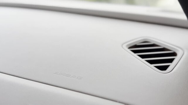 Close-up of a car dashboard with air vent and airbag area inside a clean modern vehicle interior