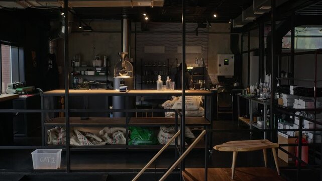 Roaster preparing equipment in artisanal coffee workshop with bean sacks and machinery. Clip fits specialty cafe branding and beverage production campaigns
