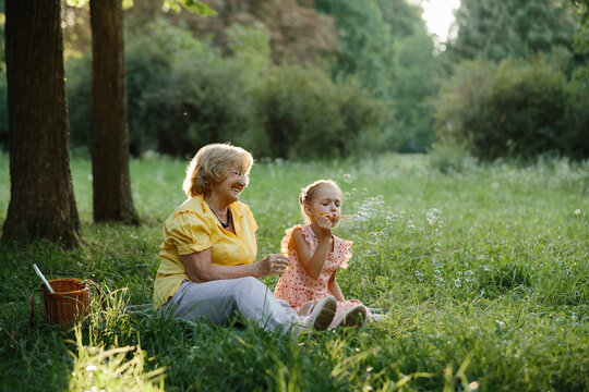 Grandmother and granddaughter enjoying summer day blowing bubbles