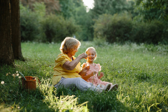 Generations bonding, grandmother and granddaughter playing with dandelions