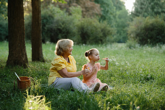 Grandmother granddaughter blowing bubbles having fun outdoors