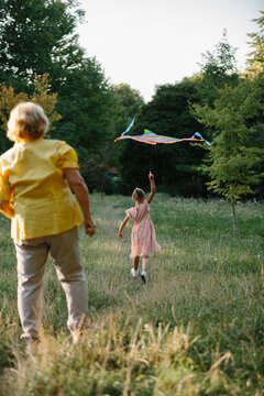 Grandmother and granddaughter playing with kite in park